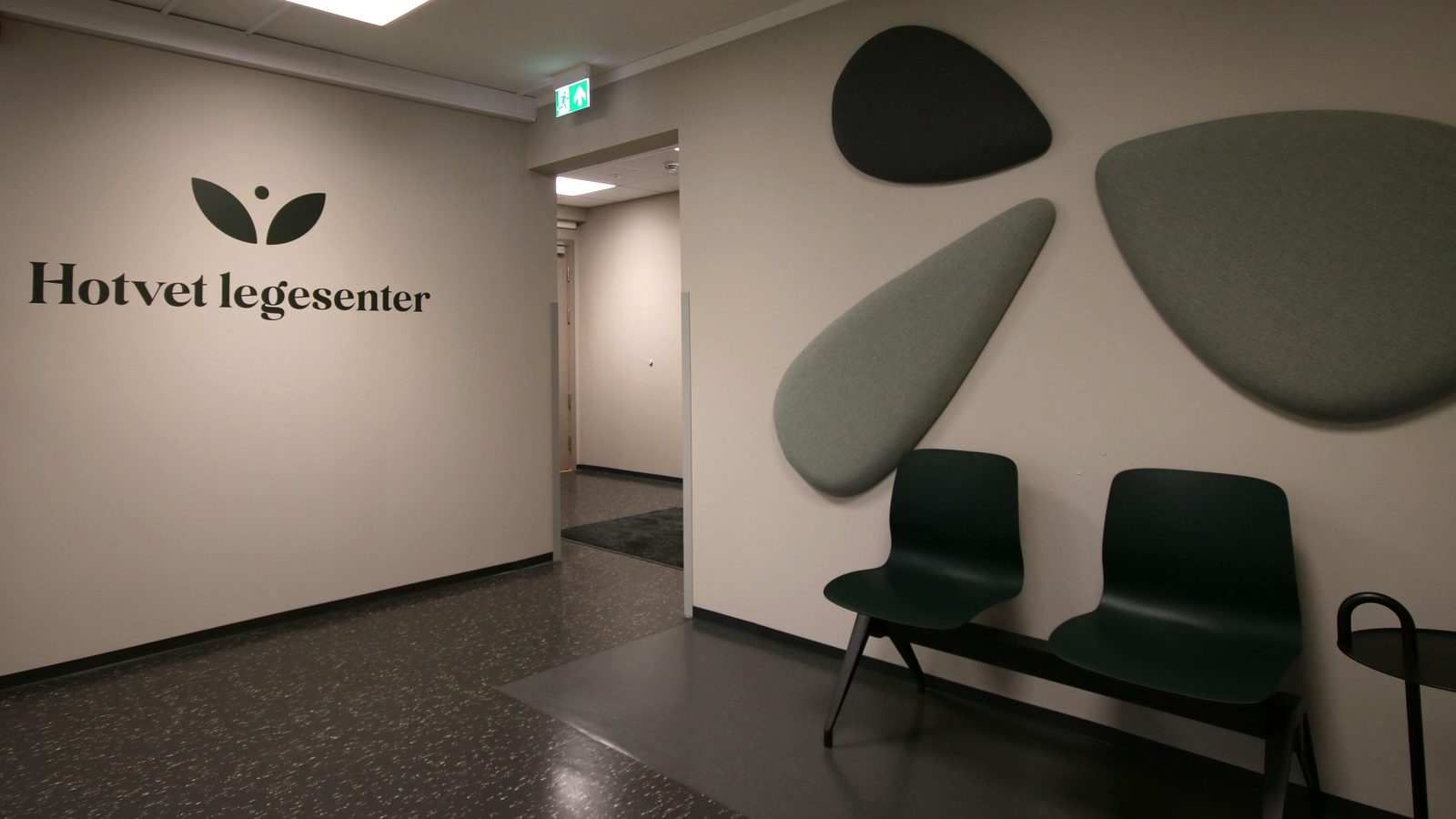 Resepsjonsområdet ved Hotvet legesenter med logoveggen og akustikkpaneler i grønt
